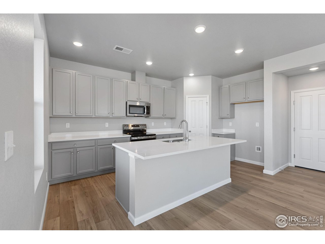 6765 Utica Court Firestone, CO 80504 - Photo 7 of 23 a kitchen with kitchen island sink stove and white cabinets