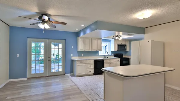 a kitchen with a refrigerator a sink dishwasher a stove and a dining table with wooden floor