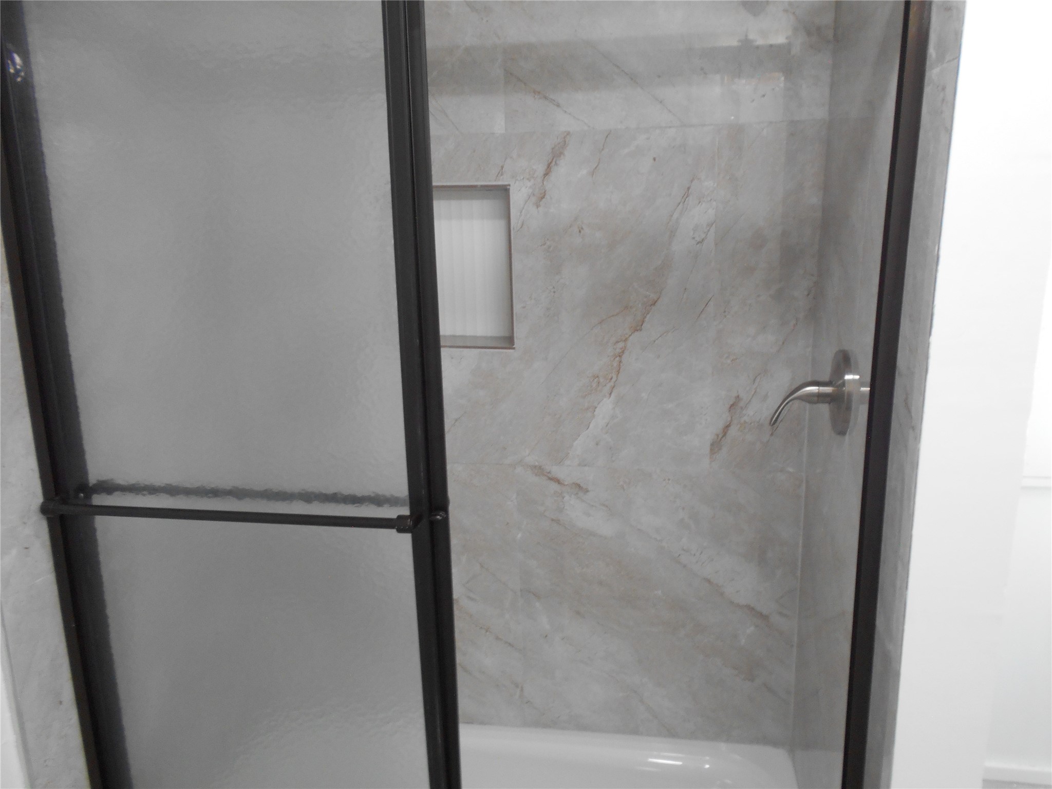 8001 Burleson Manor Road Manor, TX 78653 - Photo 19 of 31 A well-appointed shower features sleek tile walls and a convenient built-in niche.