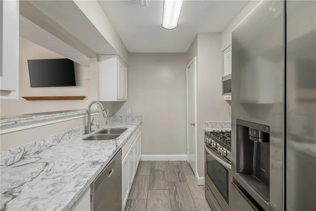 a kitchen with granite countertop a sink appliances and cabinets