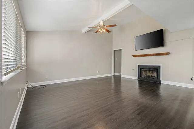 an empty room with wooden floor fireplace and windows