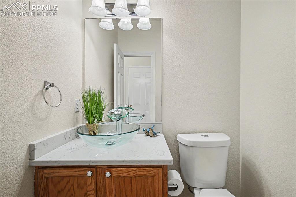 12210 Crystal Downs Road Peyton, CO 80831 - Photo 12 of 40 a bathroom with a granite countertop sink a toilet and mirror