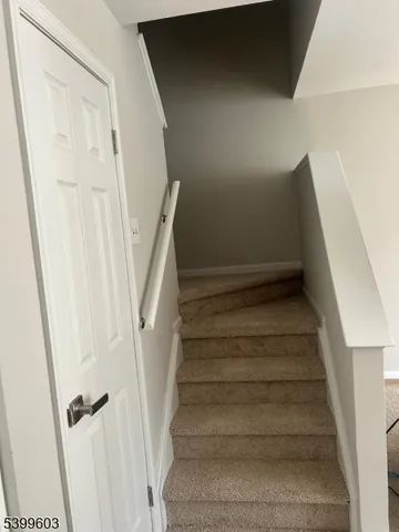 a view of staircase with white walls and white door