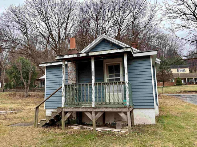 a small white house with a white roof and table and chairs next to a yard