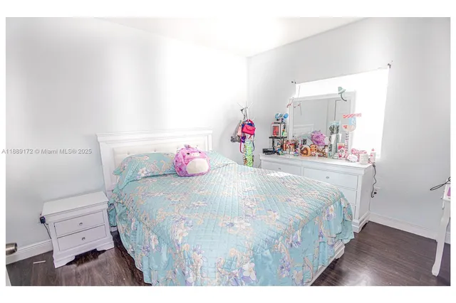 a bedroom with a bed a dresser and wooden floor