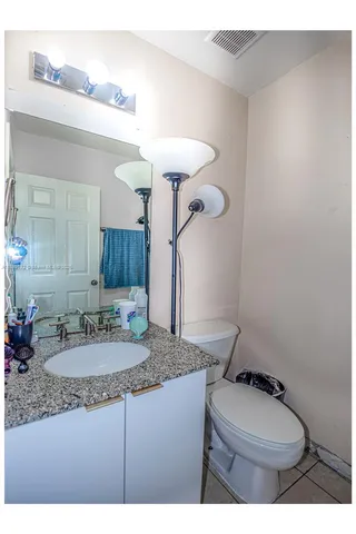 a bathroom with a granite countertop toilet sink mirror and vanity