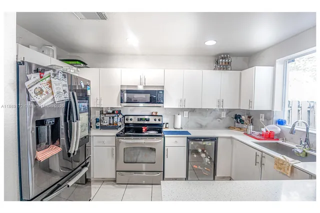 a kitchen with stainless steel appliances kitchen island granite countertop a sink window and cabinets