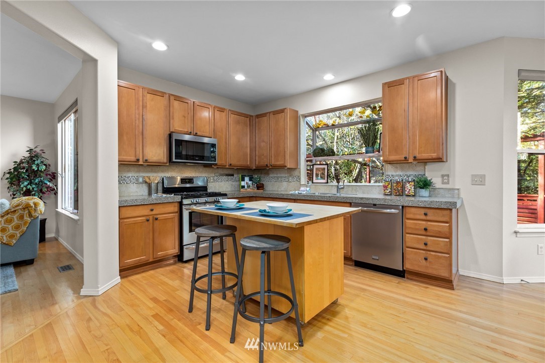 459 Field Place Northeast Renton, WA 98059 - Photo 5 of 40 a kitchen with stainless steel appliances granite countertop a stove a sink dishwasher and a refrigerator with wooden floor