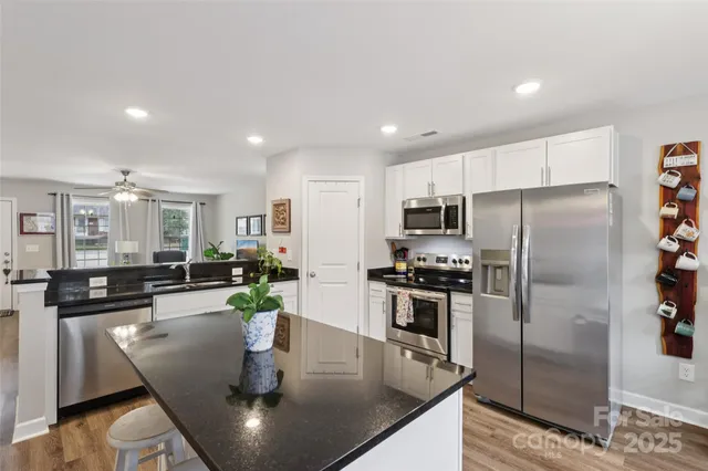 a kitchen with stainless steel appliances granite countertop a refrigerator a stove a sink a dining table and chairs