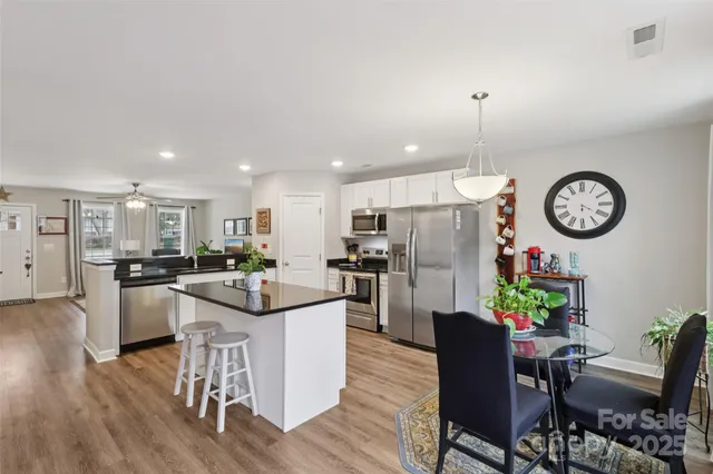 a kitchen with a dining table cabinets stainless steel appliances and wooden floor
