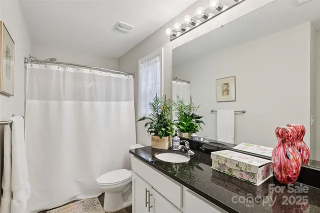 a bathroom with a granite countertop sink a toilet and a mirror