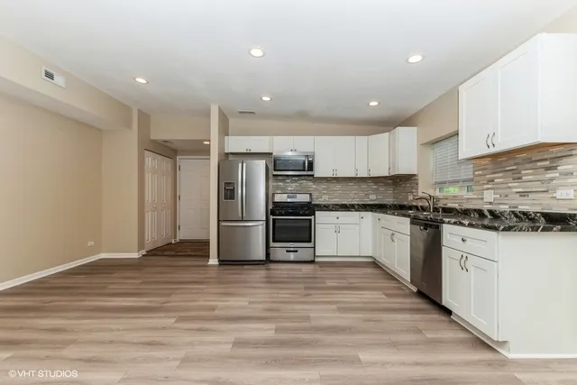a kitchen with granite countertop a refrigerator and a stove top oven
