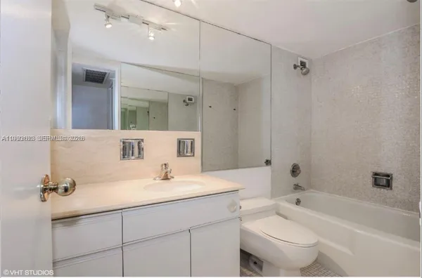 a bathroom with a sink a toilet a mirror and shower