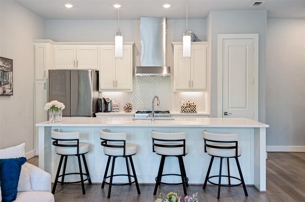 15875 Spectrum Drive, Unit 1101 Addison, TX 75001 - Photo 16 of 37 Kitchen featuring white shaker cabinetry, stainless steel appliances, a white island, pendant lighting, and wood- flooring