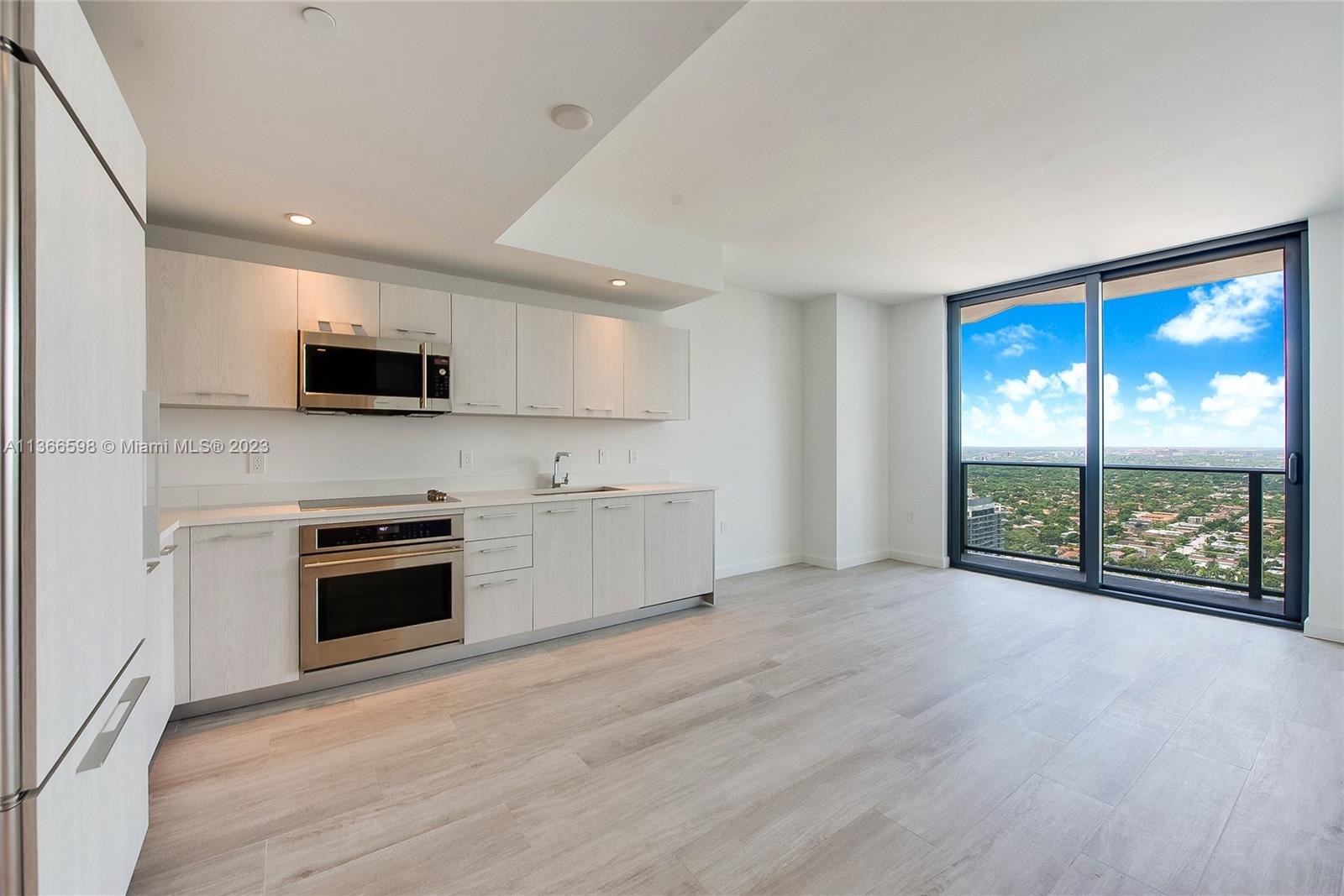 55 Southwest 9th Street, Unit 3607 Miami, FL 33130 - Photo 4 of 22 a large kitchen with stainless steel appliances granite countertop a stove a sink and a microwave