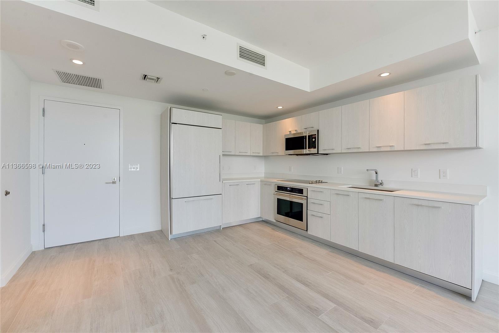 55 Southwest 9th Street, Unit 3607 Miami, FL 33130 - Photo 5 of 22 a kitchen with white cabinets and white appliances