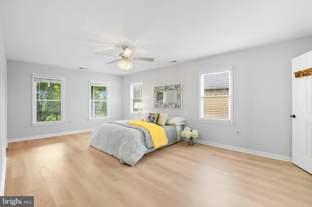 a spacious bedroom with a large bed a chandelier and windows