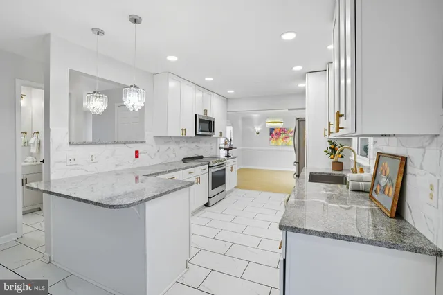 a large kitchen with kitchen island granite countertop a sink a stove and cabinets