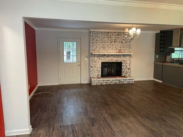 a view of an empty room with wooden floor fireplace and a window