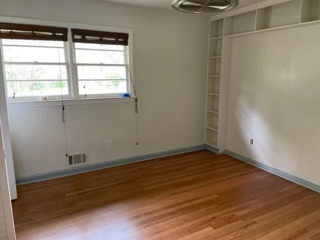 a view of an empty room with wooden floor and a window
