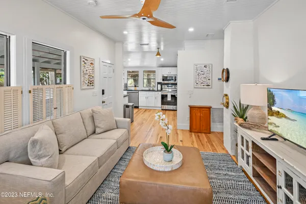 a living room with furniture and a dining table with wooden floor