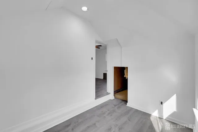 a view of an empty room with wooden floor and closet