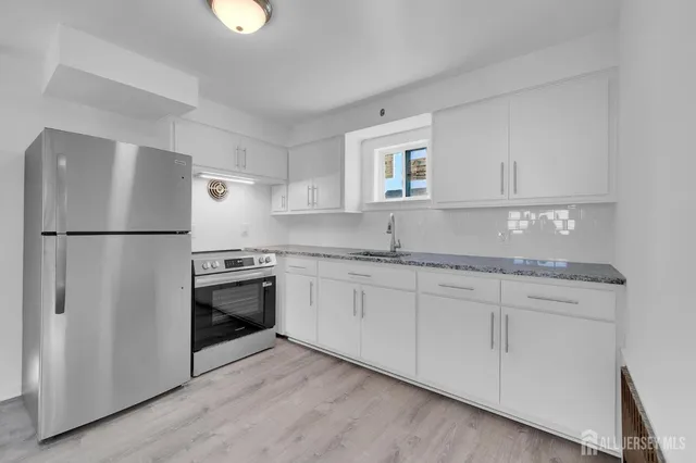 a kitchen with granite countertop a sink stove and refrigerator
