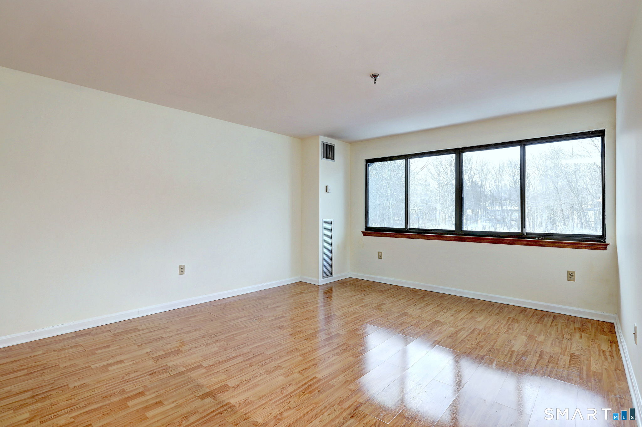 70 Putter Drive, Unit 211 Wallingford, CT 06492 - Photo 13 of 40 a view of an empty room with wooden floor and a window