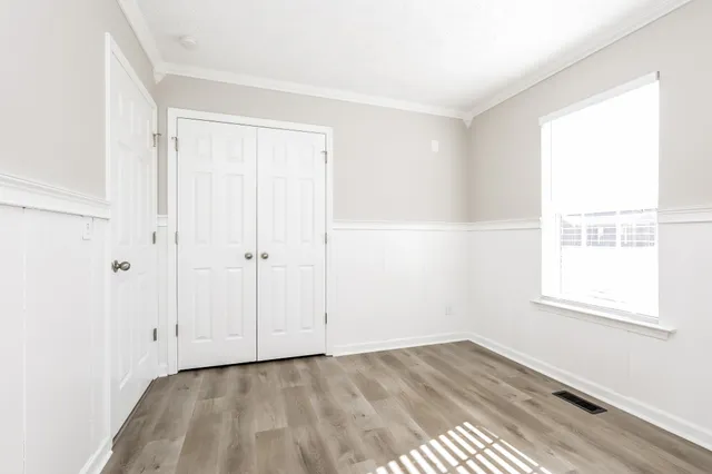an empty room with wooden floor and windows