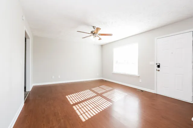 an empty room with windows and ceiling fan