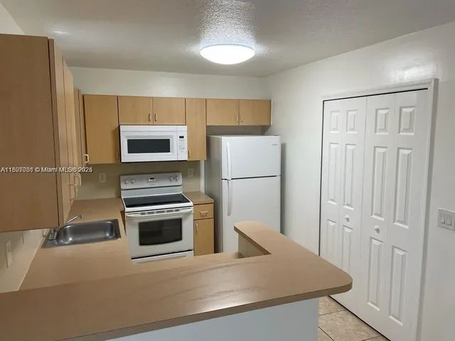 a white refrigerator freezer and a stove sitting inside of a kitchen