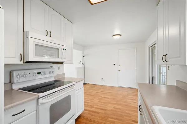 a kitchen with granite countertop white cabinets and white appliances