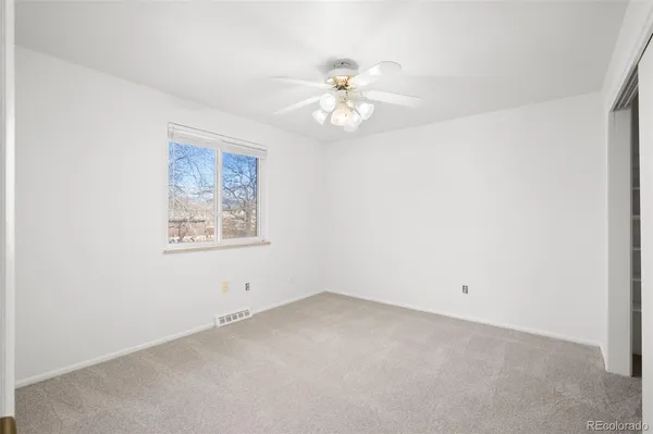 an empty room with a window and ceiling fan