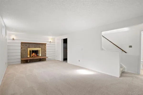 an empty room with windows and fireplace