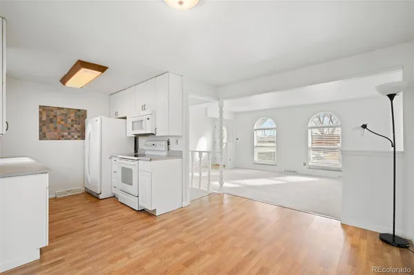 a large white kitchen with cabinets and wooden floor