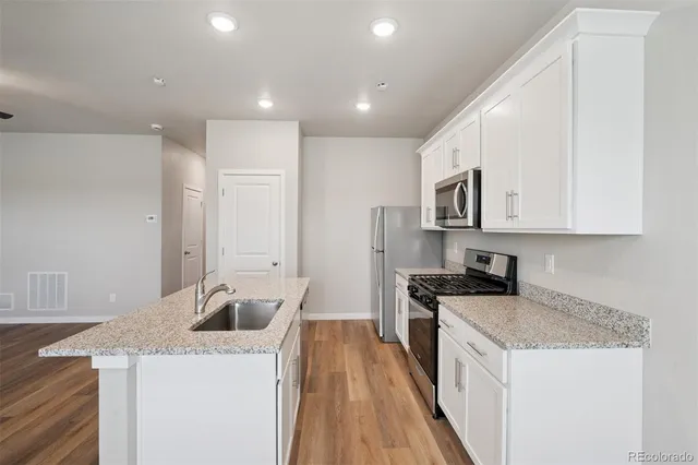a kitchen with granite countertop a sink a stove top oven a counter space and cabinets