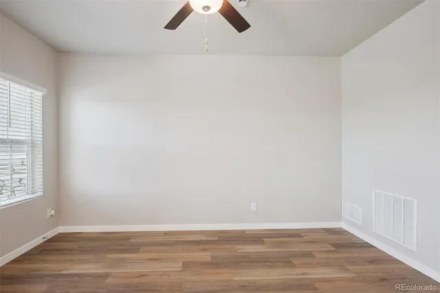 an empty room with wooden floor and windows
