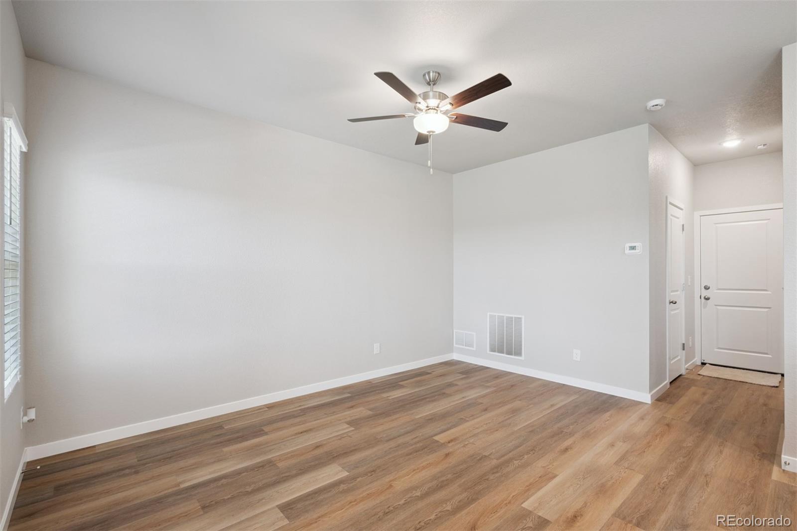921 Montbello Avenue Fort Lupton, CO 80621 - Photo 10 of 40 an empty room with wooden floor and windows