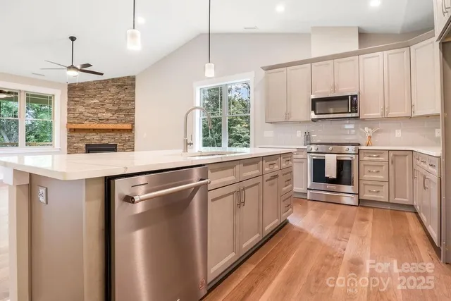 a kitchen with stainless steel appliances granite countertop a refrigerator a sink dishwasher a oven with white cabinets and wooden floor