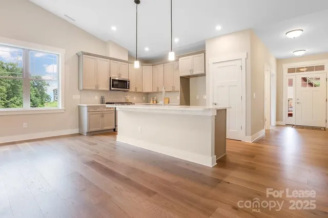 a view of kitchen with stainless steel appliances granite countertop a stove a refrigerator a sink and a wooden floor