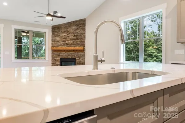 a view of open kitchen with granite countertop a large window and a sink