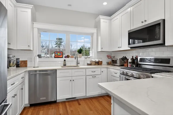 a kitchen with stainless steel appliances white cabinets sink and wooden floor
