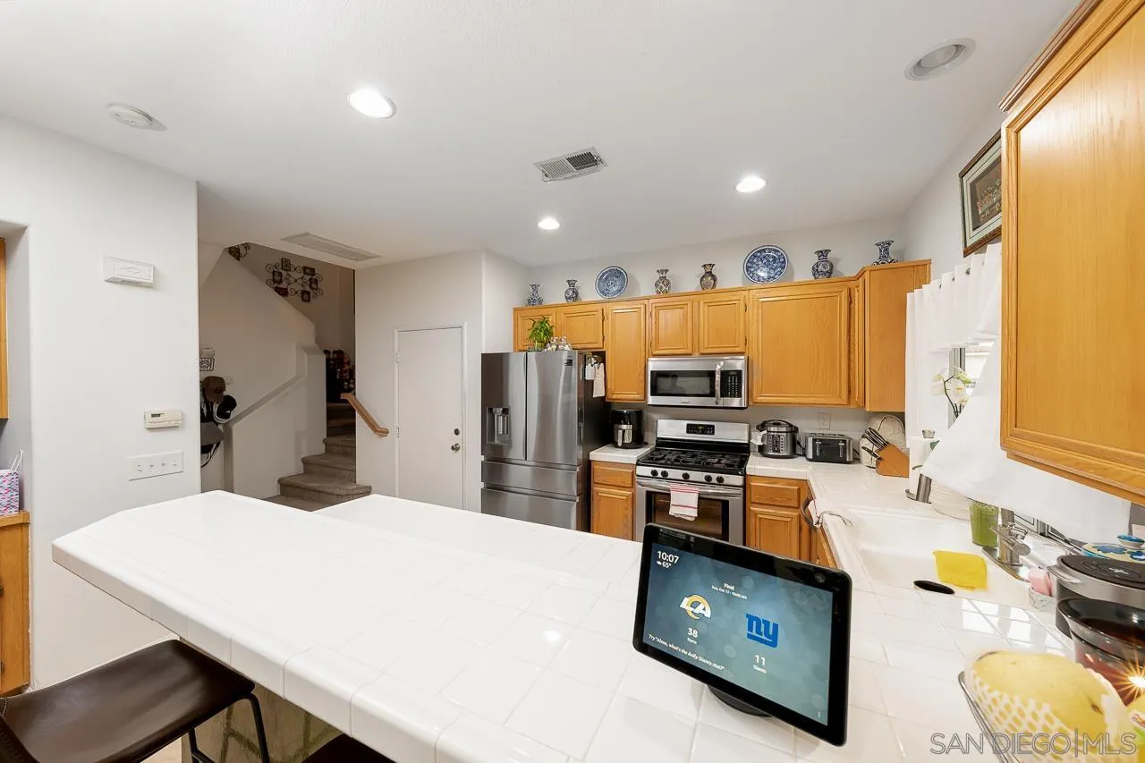 1322 Mill Valley Road Chula Vista, CA 91913 - Photo 10 of 25 a kitchen with stainless steel appliances kitchen island granite countertop a sink refrigerator and microwave
