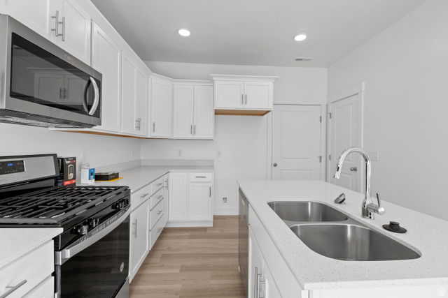1262 West 500 South Logan, UT 84321 - Photo 11 of 39 Kitchen featuring white cabinetry with silver hardware, light-toned wood-finish flooring, and white countertops
