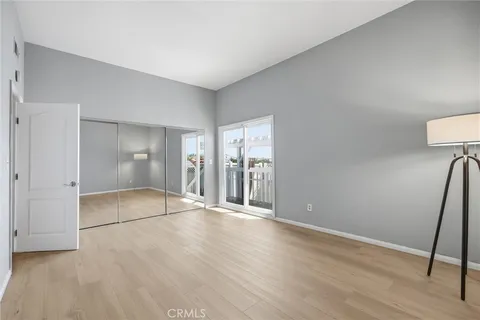 a view of an empty room with wooden floor and a bathroom