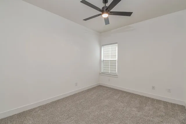 an empty room with a window and a fan