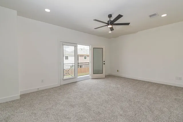 an empty room with ceiling fan and windows