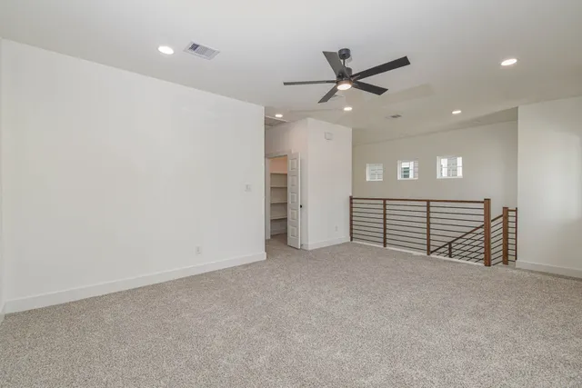 en empty room with windows and ceiling fan