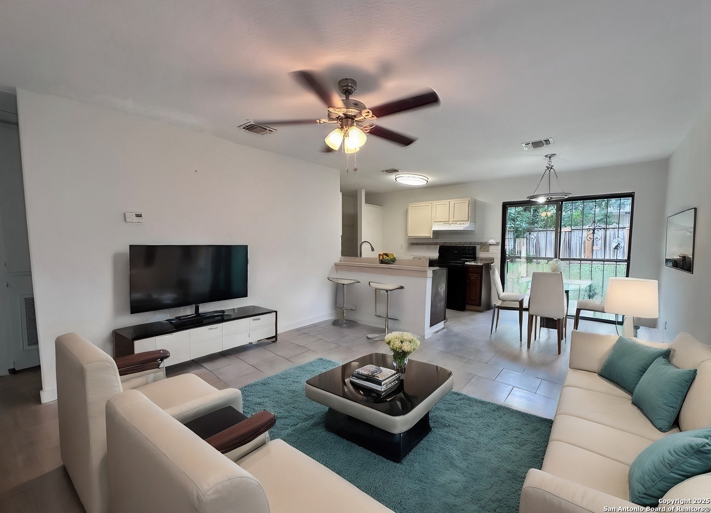 a living room with furniture and a flat screen tv with kitchen view