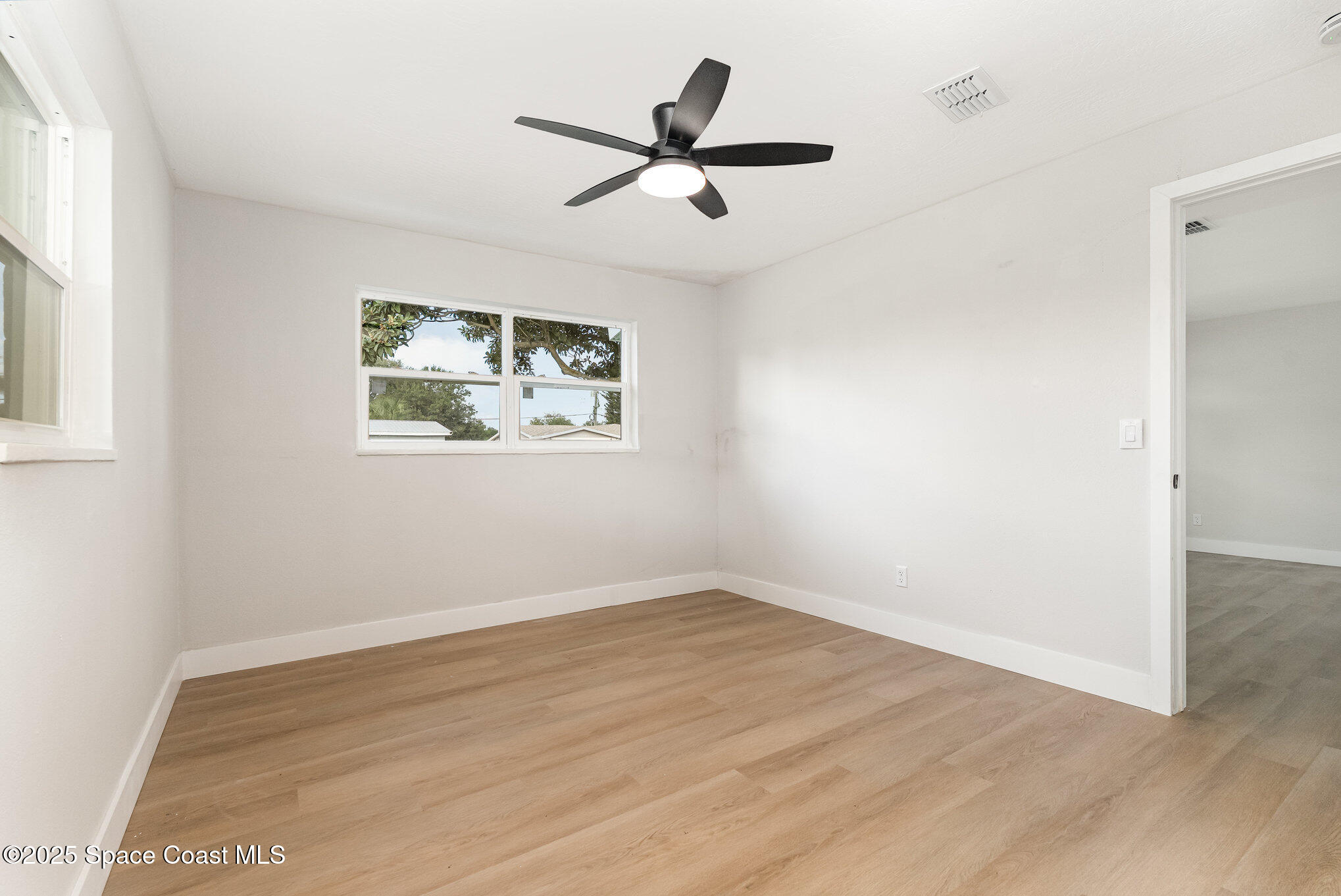 1029 Illinois Road Cocoa, FL 32927 - Photo 11 of 27 an empty room with wooden floor and windows
